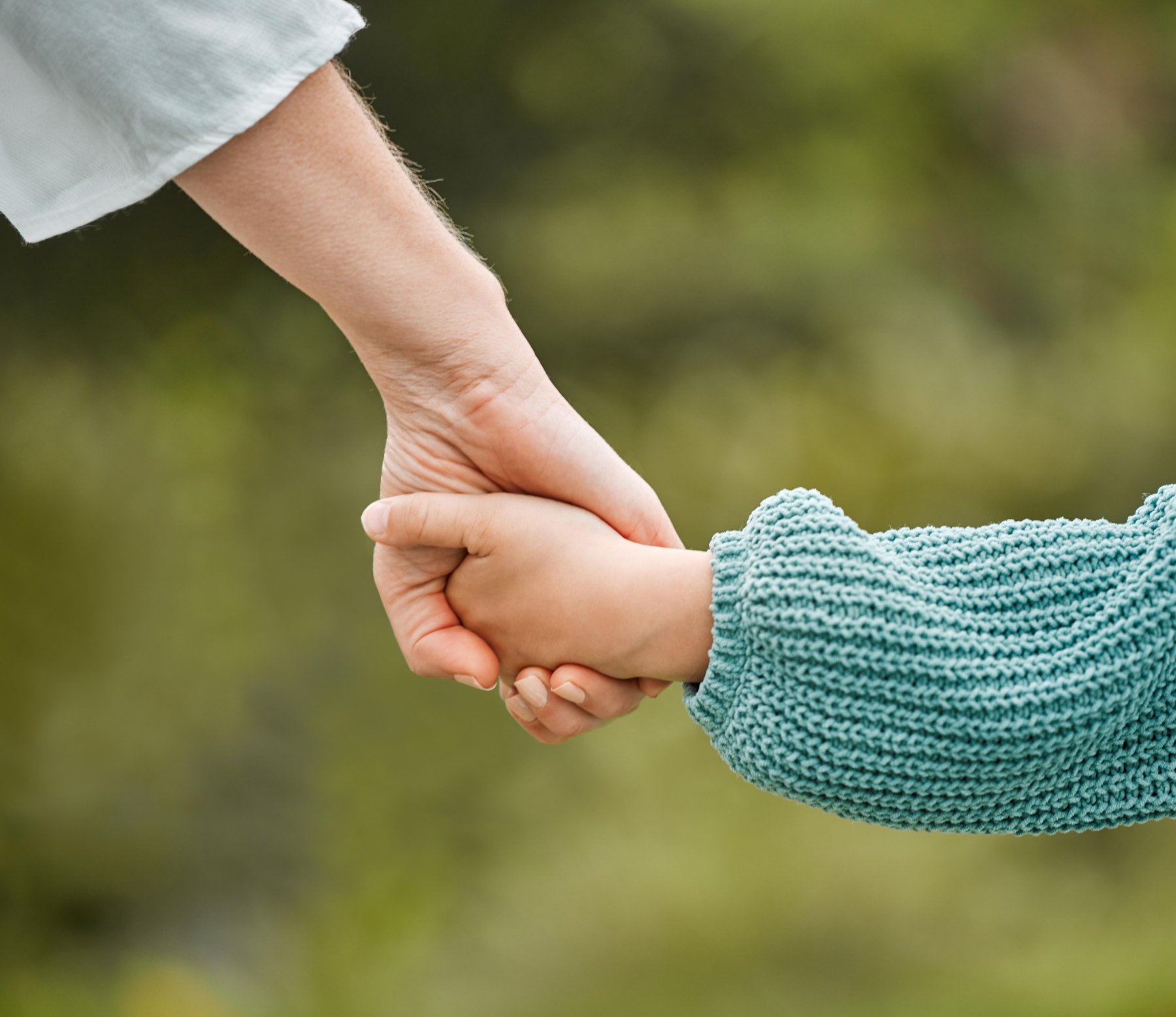 Erwachsene Hand hält die Hand eines Kindes